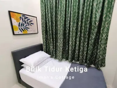 a bed with a green curtain in a room at Iman Cottage Homestay Hospital Kulim Hitech in Kulim