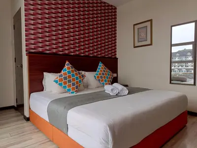 a bedroom with a large bed with a red wall at Beautiful Marigold Hotel in Tanah Rata