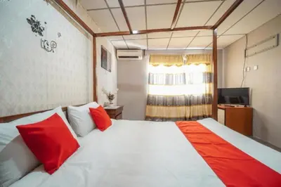 a bedroom with a large white bed with red pillows at DJ Seafront Hotel in Lumut