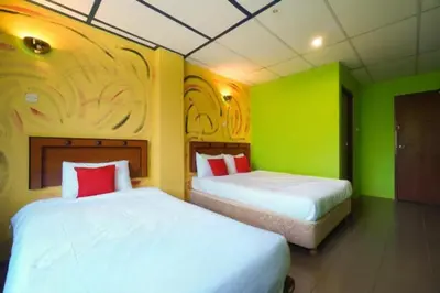 two beds in a room with green and yellow walls at DJ Seafront Hotel in Lumut