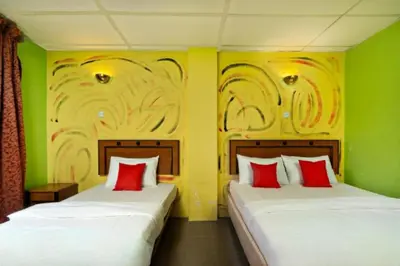 two beds in a room with green walls and red pillows at DJ Seafront Hotel in Lumut
