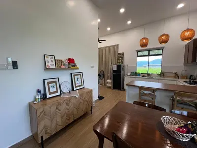 a kitchen and a living room with a table and a counter at Mai Paddy Cottage, Balik Pulau in Balik Pulau
