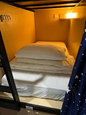 a bunk bed in a room with white pillows at Dou Houz Georgetown in George Town