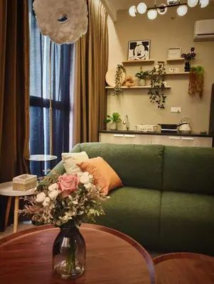 a living room with a green couch and a vase with flowers at 