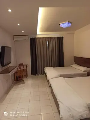 a hotel room with two beds and a television at Sunshine Lot 10 Pangkor in Kampong Sungai Udang