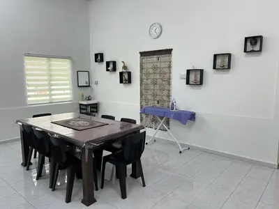 a dining room with a table and a clock on the wall at Agro Village Stay in Tapah