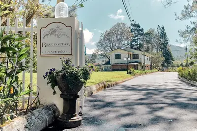 a sign on the side of a road with flowers at Rose Cottage by De'La Ferns in Tanah Rata