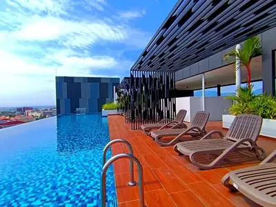 a row of chaise lounge chairs next to a swimming pool at The Horizon Ipoh Emerald by Grab A Stay in Ipoh