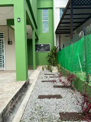 a green building with a fence and some plants at Teratak Amaris Homestay MELAYU ONLY in Sungai Petani