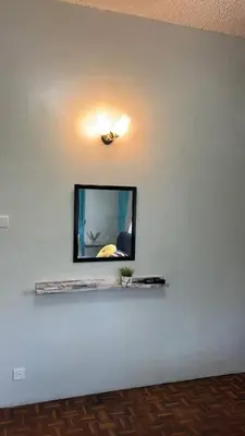 a mirror on a white wall with a shelf at The Hidden 7 in Taiping