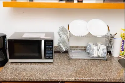 a microwave on a kitchen counter with plates and dishes at Serene Nova Family Retreat (2-6pax)near Kea Farm Market in Brinchang