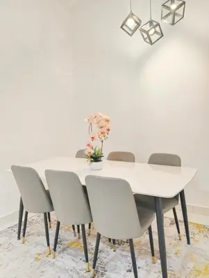 a white dining room table with chairs and a white wall at UR Homestay, Seri Iskandar in Seri Iskandar