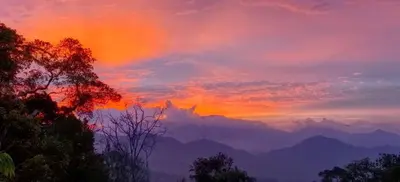 a sunset with a rainbow in the sky over mountains at Silverpar B5-5-1 Mountain View(walk up 2 floor up) in Bukit Fraser