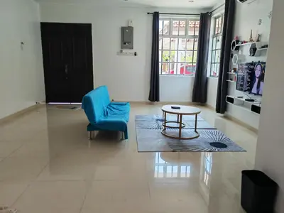 a living room with a blue chair and a table at Cozy Roomstay Padang Serai in Padang Serai