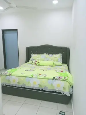 a bedroom with a bed with a green comforter and a mirror at MR OT HOMESTAY ( BAITUL RAUDHAH ) in Kepala Batas