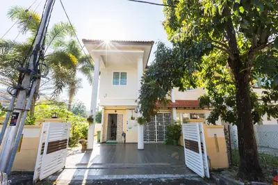 a white house with white doors and a tree at Cosy HomeStay at Penang Island -Beach and Village in Bayan Lepas