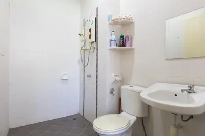 a white bathroom with a toilet and a sink at Cosy HomeStay at Penang Island -Beach and Village in Bayan Lepas