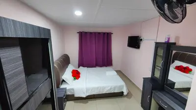 a small room with a bed with red flowers on it at Santai Desa Chalet musleem 0nly in Brinchang
