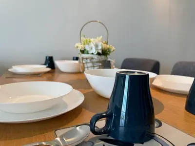 a wooden table with white plates and a blue vase at 【NEW】Harmony’s Home@Juru Sentral Icon City in Bukit Mertajam
