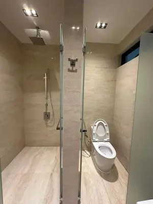 a bathroom with a toilet and a glass shower stall at coolvibes homes in Cameron Highlands