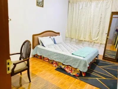 a bedroom with a bed with a chair and a window at HOMESTAY DSENJA in Kepala Batas