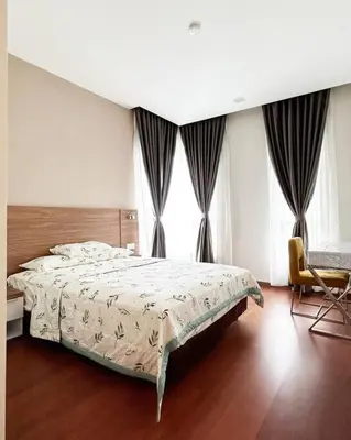 a bedroom with a bed and a chair and windows at Ipoh Tambun Private Unit Lakeside Residences in Kampong Batu Lapan