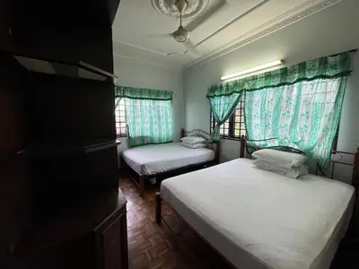 two beds in a room with two windows at Happy Homestay in Ipoh