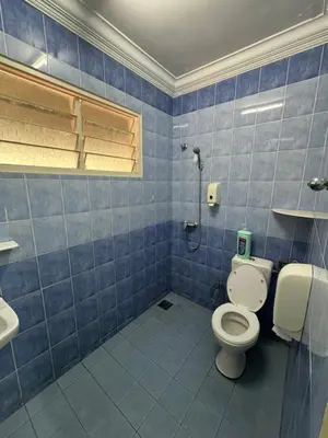 a blue tiled bathroom with a toilet and a sink at Happy Homestay in Ipoh