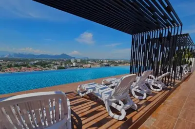 a row of chairs on a deck with a view of the water at Cozy Urban Retreat @ Horizon in Ipoh