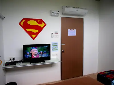 a tv with a superman sign on a wall at Fang Zu Ming Concept Guesthouse in Ayer Itam