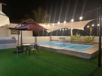 a pool with chairs and a table and an umbrella at AYRA HOMESTAY in Kuala Kangsar