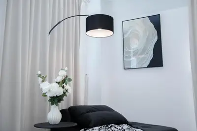 a living room with a vase of flowers and a lamp at Batu Ferringhi By The Sea Luxurious 2BR Suite 6 Pax in Batu Ferringhi