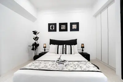 a bedroom with a large bed with white walls at Batu Ferringhi By The Sea Luxurious 2BR Suite 6 Pax in Batu Ferringhi