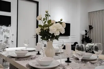 a table with a vase with white flowers on it at Batu Ferringhi By The Sea Luxurious 2BR Suite 6 Pax in Batu Ferringhi