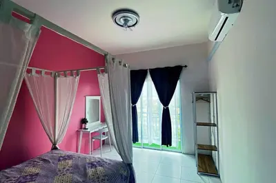 a bedroom with a bed and a pink wall at R&R Manjung Guest House at Pangsapuri Samudera in Seri Manjung