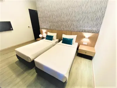 a hotel room with two beds and a tv at Corner Club Penang in George Town