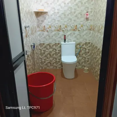 a bathroom with a toilet and a red bucket at teratai ciknah in Penaga