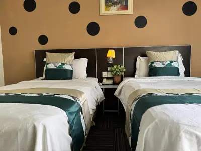 two beds in a hotel room with white and green sheets at K Garden Hotel (BS) in Bagan Serai
