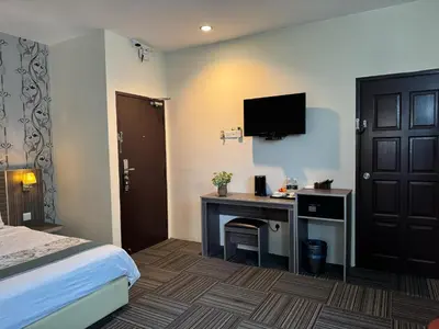 a hotel room with a desk and a tv on the wall at K Garden Hotel (BS) in Bagan Serai