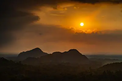 a sunset over a mountain range with the sun in the sky at Sebayu Retreat Gopeng in Gopeng