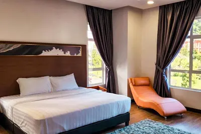 a bedroom with a bed and a chair and windows at ZINNIA RESIDENCE in Tanah Rata