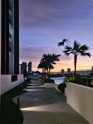 a walkway with palm trees in a city at dusk at Metropol Serviced Apartment Bukit Mertajam Perda in Bukit Mertajam