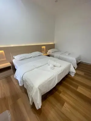 two beds in a room with white sheets at Adik aisyah teres golden hill Cameron Highlands in Brinchang