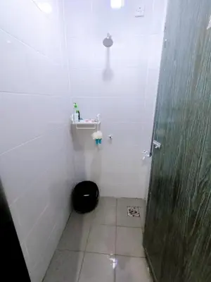 a white bathroom with a shower and a black seat at Manjung Point Homestay in Seri Manjung