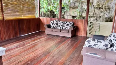 a porch with a couch and chairs on a wooden floor at Country house Pulai Holiday Village in Gua Musang