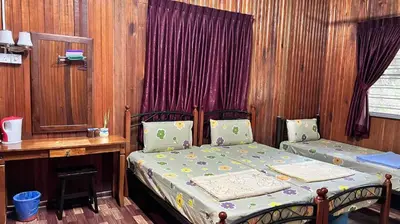 a bedroom with two beds and a wooden wall at Country house Pulai Holiday Village in Gua Musang