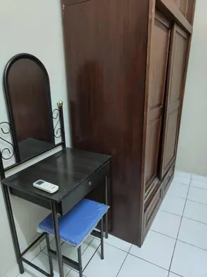 a wooden dresser with a mirror and a blue chair at HomeStay Pulai in Ipoh