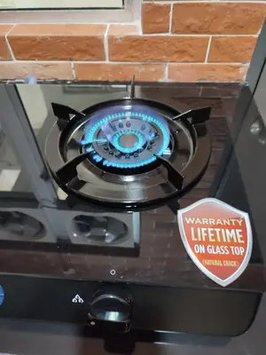 a gas stove with a sign that reads warranty lifeline on glass top at Adik aisyah muji pistachio homestay cameron highlands in Tanah Rata