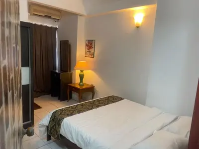 a bedroom with a bed and a lamp on a table at HOMESTAY ANGGUN SAFIYYA in Bayan Lepas