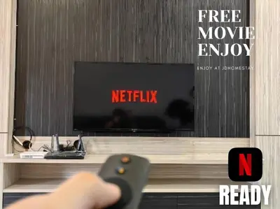a person holding a remote control in front of a tv at 【Ipoh Garden】4Br/8pax All Attractions w/in 15mins in Ipoh